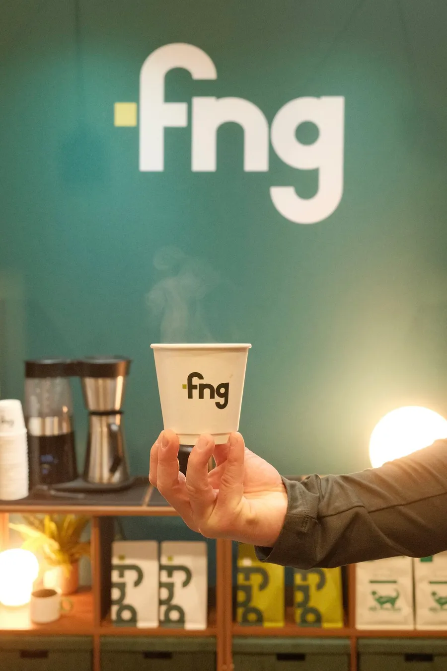 An FNG-branded coffee cup held up at the FNG booth